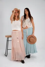 Pollera larga de color rosa pálido, con corte en capas y cintura elastizada. Incluye lazo fino del mismo material.