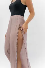 Pantalón blanco de gasa liviana con cintura elástica y aberturas laterales con detalle de pompones.