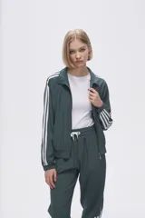 Campera deportiva verde con cierre frontal, cuello alto y tres rayas blancas en las mangas.