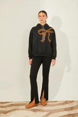 Buzo negro de frisa oversize con capucha y bordado de moño print animal en gamuza en el delantero.