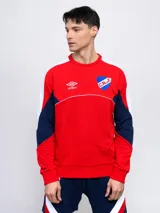 Buzo de felpa rojo, con mangas blancas y recortes en azul marino. Logo de Umbro bordado en el pecho y escudo del Club Nacional de Football.