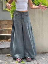 Pantalón de jean ancho, color verde oscuro o gris verdoso, de tiro alto con pliegues frontales y corte extremadamente holgado.