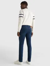 Jeans de denim azul oscuro con efecto desteñido en la parte delantera, corte ajustado, cierre de cremallera con botón y diseño de cinco bolsillos.