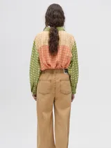 Mono largo de jean celeste con corte holgado, cintura elastizada con cordón ajustable, sin mangas, cuello camisero y cierre frontal con botones. Presenta bordados de motivos playeros en el pecho.