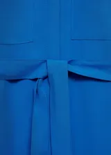 Vestido camisero midi color azul eléctrico, con cuello camisero, manga larga con puños abotonados, dos bolsillos de parche en el pecho, lazo ajustable en la cintura, cierre frontal con botones y aberturas laterales en el bajo.