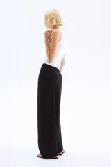 Pantalón sastre negro de punto crepé con pinzas, tiro alto, cintura elástica, cinturón decorativo con hebilla metálica y piernas amplias rectas.
