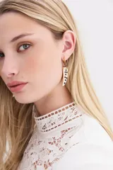 Aros colgantes dorados con forma de argolla pequeña y dije en forma de cuerno de resina con incrustaciones de strass.