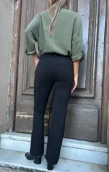 Pantalón negro de corte recto con bota levemente acampanada, de algodón y lycra, con pretina con presillas, elástico y faja.