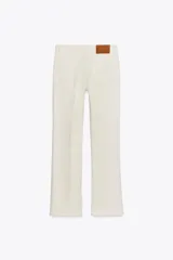 Pantalón de jean azul oscuro, de tiro bajo, corte slim fit y bootcut. Con cinco bolsillos y cierre frontal con cremallera y botón.