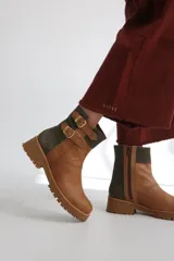 Botas cortas de gamuza color marrón con detalles dorados y hebillas decorativas.