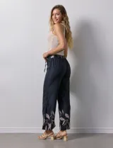 Pantalón negro con estampado de hojas color rosa en el ruedo y cintura elastizada con lazo ajustable.