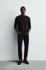 Pantalón de jean negro, corte slim fit, con tiro medio, cinco bolsillos, efecto lavado y cierre frontal con cremallera y botón.
