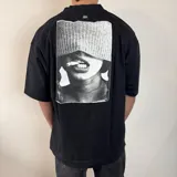 Remera negra de corte oversize y mangas cortas, con estampa en la espalda de una fotografía en blanco y negro de una persona fumando.
