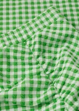 Falda midi de tiro alto con estampado a cuadros vichy en verde y blanco, con frunce lateral y abertura en el ruedo.