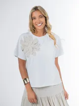 Remera blanca de tejido liviano con aplique de flor tejida en crochet en el frente. Diseño básico de corte recto y mangas cortas.