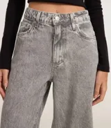 Pantalón wide leg de jeans gris lavado, tiro alto, con bolsillos delanteros y traseros, cierre con botón y cremallera.
