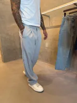 Pantalón de vestir de corte sastrero holgado (oversize) color gris claro, con pliegues frontales y cierre de cremallera.