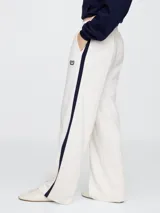 Pantalón deportivo azul marino de corte recto, con cintura elástica, bolsillos laterales y logo de Gap bordado en blanco. Presenta una franja blanca vertical en los laterales.