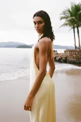Vestido midi de satén color amarillo pálido, con cuello halter y espalda descubierta.