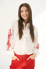 Camisa blanca de manga larga con bordados florales marrones en las mangas.