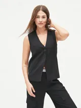 Chaleco sastre negro, sin mangas, con escote en V profundo y cierre frontal de botones. Presenta un bolsillo superior simulado en el lado izquierdo.