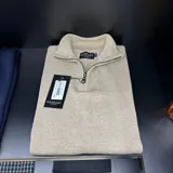 Buzo color beige con cuello polo y cierre metálico a la mitad del frente.
