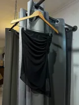 Top negro con diseño asimétrico y detalles drapeados.