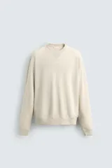 Sudadera color beige claro con cuello redondo y mangas largas.