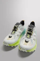 Zapatilla deportiva para carreras de montaña, color blanco con detalles en gris, verde y amarillo. Parte superior fabricada en tejido de punto transpirable con zona de puntera y talón recubiertas de material Shield Protect Max que protege de la abrasión. Ajuste de los cordones mediante pieza técnica. Tirador en la parte posterior para facilitar el calce. Plantilla interior OrthoLite® extraíble. Suela con tecnología Spume Foam que garantiza ligereza y confort.