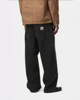 Pantalón de denim negro de corte ancho y holgado, con tiro bajo y etiqueta de marca cuadrada en el bolsillo trasero derecho.