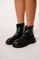 Botas de eco-cuero negro con cierre trasero y suela plana, diseño contemporáneo.