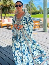 Vestido largo de polysilk con estampado paisley en tonos azul, celeste y dorado. Tiene escote en V, mangas largas acampanadas y corte amplio.