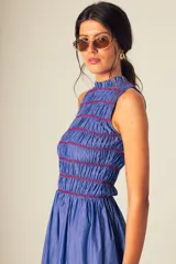 Vestido midi a rayas verticales azules y blancas, con cuerpo superior fruncido y falda amplia. Presenta un detalle de flor roja en el hombro.