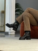 Bota corta negra de cuero con hebillas plateadas y suela track.