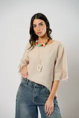 Blusa beige de lino con mangas 3/4 con lazos y detalle de flecos en los puños.