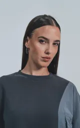 Buzo gris oscuro de cuello redondo, corte oversize y largo crop. Presenta un bolsillo grande de microfibra gris claro en el frente.