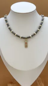 Collar de cuentas grises y blancas con dijes dorados con incrustaciones de circonitas.