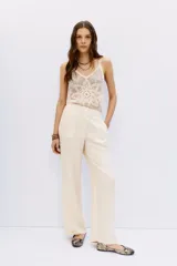 Pantalón de vestir ancho color crema, tiro alto, con pliegues frontales y bolsillos laterales.