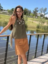 Top color beige de cuero con flecos en los laterales y caracoles buzios en el frente. Espalda tejida.