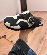 Zueco con estampado de vaca en blanco y negro, con hebilla metálica plateada y plantilla de corcho.