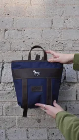 Mochila pequeña color borgoña con detalles en cuero marrón, asa de mano y correas ajustables.