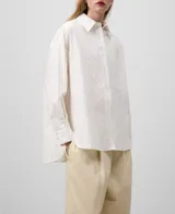 Camisa blanca de algodón con finas rayas verticales. Tiene cuello solapa, cierre con botones, manga larga con puño, bolsillo en el pecho y canesú en la espalda.