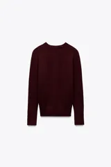 Sweater negro de punto liso con cuello redondo y mangas largas con botones dorados en los puños.