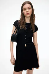 Saco corto negro en punto acanalado fino de mezcla de viscosa. Modelo entallado de manga corta con cuello redondo y cierre de botones.