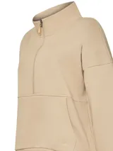 Buzo color beige de algodón orgánico, con medio cierre, cuello alto, bolsillo canguro y bordado delicado.