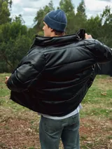 Campera puffer negra de poliéster con cuello alto, cierre frontal con cremallera, bolsillos laterales con solapa y puños elásticos.