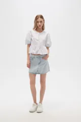 Blusa de algodón a rayas verticales color celeste y blanco, con cuello redondo, mangas cortas abullonadas y corte peplum.