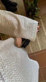 Blusa plateada de tejido metalizado, con escote en bote que puede usarse recto o caído en un hombro.