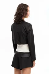 Blazer corto color blanco, de manga larga con solapa y bolsillo de pecho en tela brillosa.