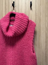 Chaleco tejido de punto grueso color fucsia, con cuello alto y sin mangas.